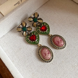 Macro detail of vintage heart earrings with cameo drop and red crystal