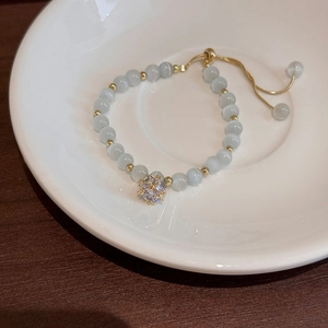 Detail view of an adjustable cat eye stone bracelet with a sparkling rhinestone pendant
