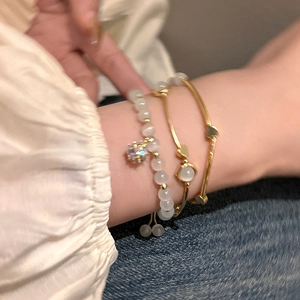 Detailed view of elegant cat's eye stone bead bracelet and gold bangles set on wrist