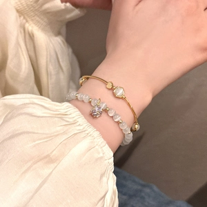 Detailed view of elegant gold bangle with cat-eye stone and purple crystal beaded bracelet