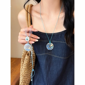 Detailweergave van een schelpenketting met blauw koord voor strandvakantie stijl.