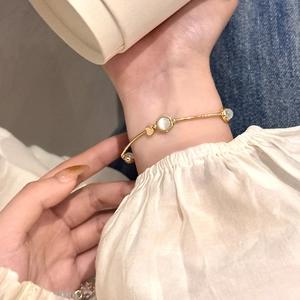 Close-up of an elegant gold bracelet with shimmering cat eye stones on a woman's wrist
