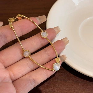 Detailed view of elegant golden adjustable bracelet featuring white cat-eye stones