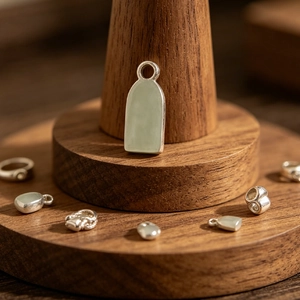 Detailed view of stainless steel arched pendant on a wooden jewelry display stand