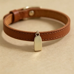 Close-up macro view of blank stainless steel rectangular pendant on brown leather strap