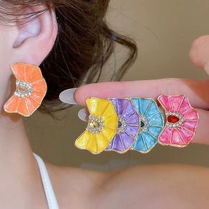 Detalle de pendientes de flores plisadas de colores con esmalte y brillantes diamantes