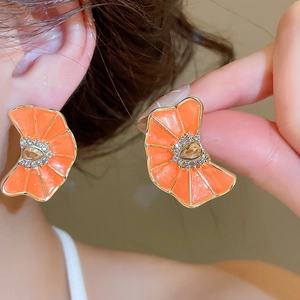 Vista de detalle de pendientes de abanico floral naranja con diamantes de imitación en oreja