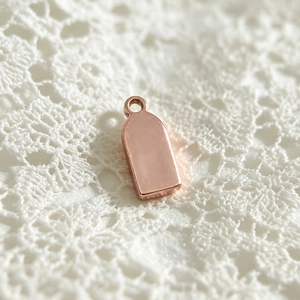 Detailed macro view of a rose gold rectangular stainless steel pendant on white lace background