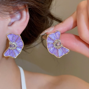 Primer plano de pendientes de flores moradas con pedrería y acabado al aceite