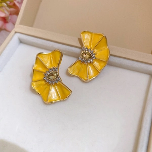 Primer plano detallado de pendientes de flor plisada en esmalte amarillo con brillantes strass