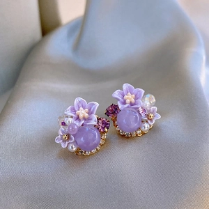 Macro-opname van elegante paarse bloem oorknoppen met parels en glanzende kristallen