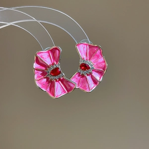 Primer plano de pendientes de flores de esmalte rosa con cristal rojo en el centro