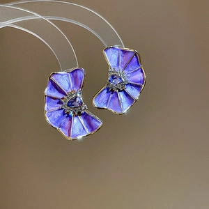 Primer plano de pendientes de flores plisadas púrpuras con piedra azul y brillantes