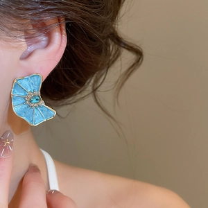 Primer plano de elegante pendiente de flor de esmalte azul con diamantes
