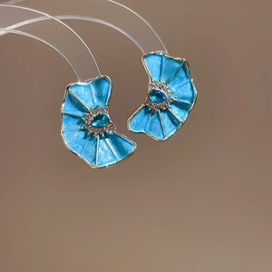 Primer plano de pendientes de flor de esmalte azul con cristal de gota