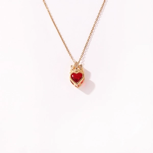 Detailweergave van elegante rode hartjesketting met gouden kroonversiering op wit