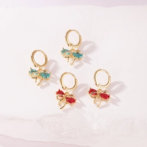 Macro detail view of gold-plated hoop earrings featuring sparkling zircon bow pendants