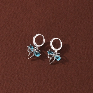 Detailed view of bow-shaped earrings with sparkling blue zircons in a silver finish