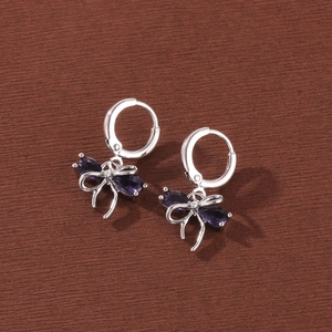 Close-up of elegant bow-shaped hoop earrings with sparkling purple zircon stones.