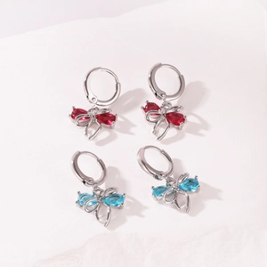 Detailed view of bow-shaped hoop earrings with sparkling red and blue zircons.
