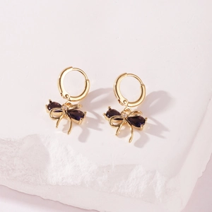 Close-up of elegant gold-plated hoop earrings with purple zircon butterfly bow dangles