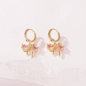 Macro view of gold-plated copper hoop earrings featuring pink zircon bowknot charms
