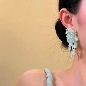 Vue détaillée d'élégantes boucles d'oreilles fleuries à franges en perles bleues portées