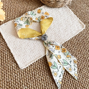 Close-up detail of the French tulip floral print scarf necklace with soft yellow fabric.