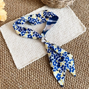 Close-up of French summer silk scarf necklace with blue tulip pattern and pearl bead.