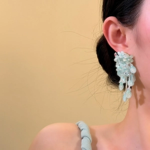Vue détaillée des boucles d'oreilles à fleurs en perles bleu clair portées par un mannequin
