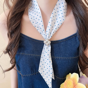 Close-up of French style silk scarf necklace with floral clasp and polka dot pattern.