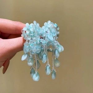 Vue détaillée des boucles d'oreilles à pompons en perles bleues avec motifs floraux.