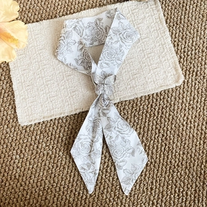 Close-up detail of a French style floral silk scarf necklace featuring a silver butterfly buckle