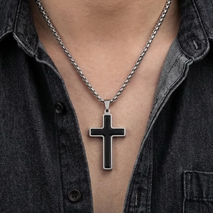 Gros plan d'un pendentif en croix bicolore en acier inoxydable sur le cou d'un homme.
