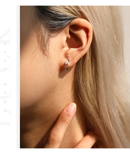 Detailed view of a silver pear-shaped moissanite hoop earring worn on an ear.