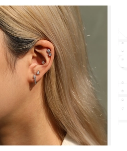 Detailed macro view of teardrop Moissanite hoop earrings and silver studs on the ear