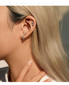 Macro view of sterling silver waterdrop hoop earrings and studs with moissanite on ear