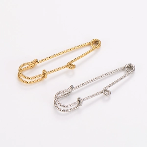 Detalle de imperdibles de acero inoxidable chapado en oro 18k con diseño de corte diamante