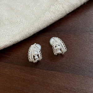 Detailed view of French-style pearl ear clips with sparkling stones on wooden background