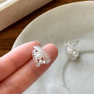 Close-up detail view of elegant French style pearl earrings with intricate lace metalwork.