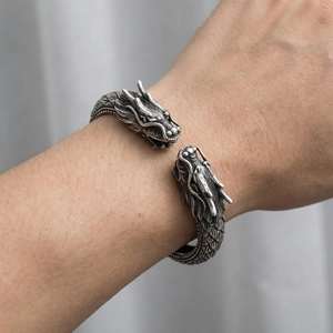 Vue détaillée des sculptures de tête de dragon sur un bracelet jonc punk en acier