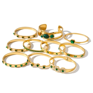 Detailed view of gold stainless steel bangles with green heart and gemstone accents