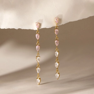 Detail view of long gold drop earrings with pink and clear teardrop cubic zirconia