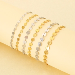 Minimalist stainless steel disc chain bracelet and anklet set in gold and silver finishes.
