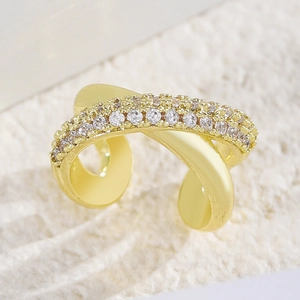 Detailed macro shot of gold X-shaped crossover ear cuff with cubic zirconia stones