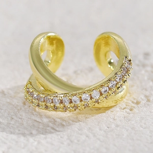 Macro detail of a gold-plated crisscross X ear cuff with shimmering zircon stone inlays