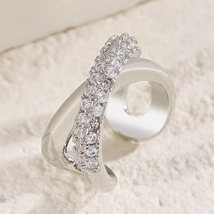 Macro detail of a silver crossover ear cuff inlaid with shimmering cubic zirconia stones