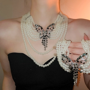 Vue détaillée du collier de perles multicouches avec pendentif papillon en strass brillant.