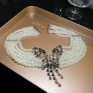 Gros plan d'un collier de perles élégant à plusieurs rangs avec pendentif papillon