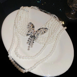 Détail macro d'un collier de perles françaises à plusieurs rangs avec un papillon